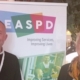 Photo of Elena Weber and Philippe Belseur standing by a EASPD poster