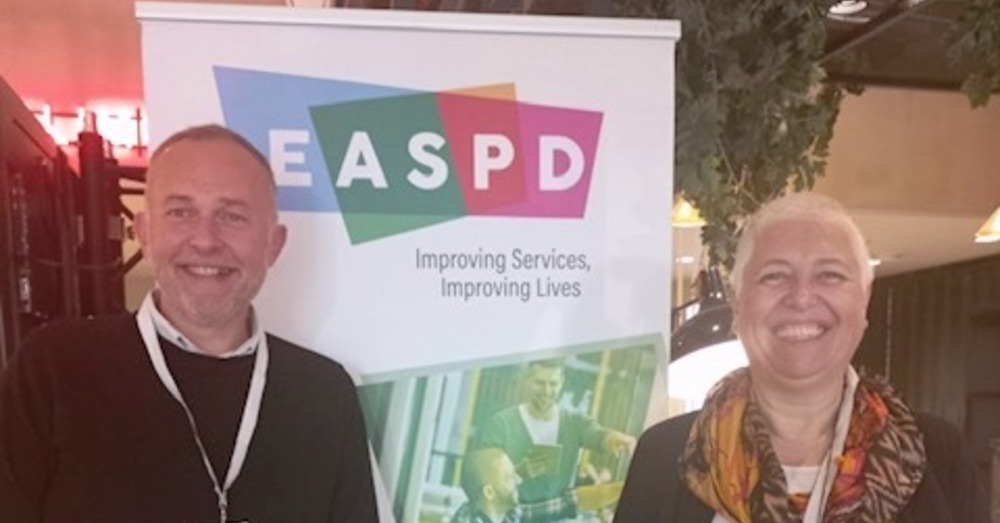 Photo of Elena Weber and Philippe Belseur standing by a EASPD poster